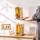 Een persoon die twee book nooks in Robotime Dust Covers WD1001 op elkaar stapelt