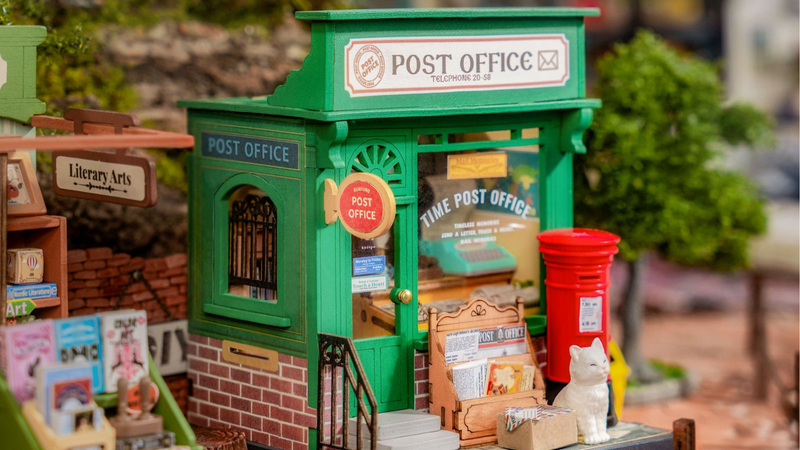 Monique post een brief in het miniatuur postkantoortje met Rolifes houten bouwpakket
