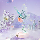 Sfeervolle presentatie van de Robotime Butterfly (Pink), elektrisch bouwpakket van een lichtblauwe vlinder die kan flapperen met zijn vleugels, op een roze bloem