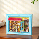 Sfeervolle presentatie van de Robotime Fluffy Cat Bakery, diorama in een lijst van een bakkerijtje met een kat