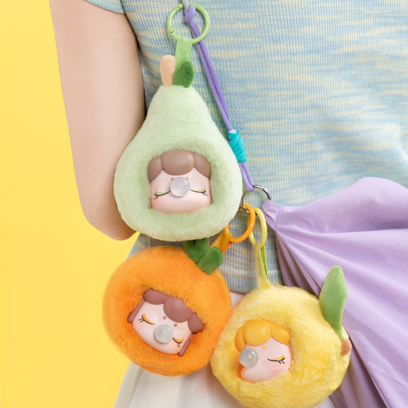 Pear, Orange en Lemon varianten van de Robotime Nanci Fruit Mood Surprise Plush Pendant blind box serie, hangend aan een tas