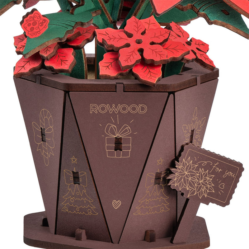 Close-up van de pot, het bordje en een paar kleine bloemetjes van de Robotime Poinsettia