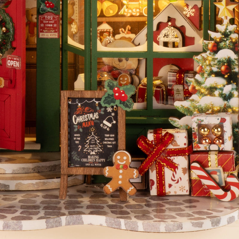 Close-up van de etalage, kerstboom met cadeautjes en winkelbord van de Robotime Santa’s Toy Shop